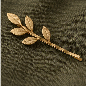 Matte brass leaf hair pin on olive green fabric