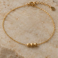 Fine gold-tone anklet with three small beads on pale stone
