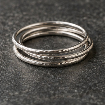 Three slim sterling silver stacking rings on charcoal stone