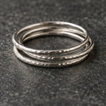 Three slim sterling silver stacking rings on charcoal stone
